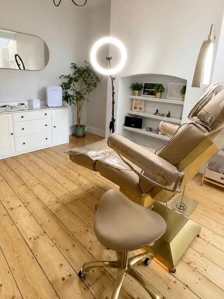 A modern beauty treatment room with a ring light and reclining chair.