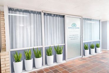 Office entrance with potted plants and frosted glass door.