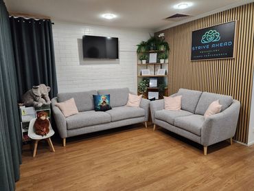 Cozy modern waiting room with gray sofas and stuffed animal decor.