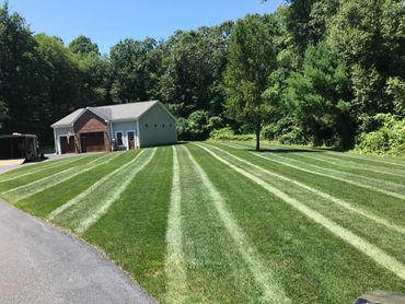 A neatly mowed lawn with striped patterns in front of a garage.