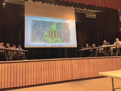 Meeting with aerial map presentation on stage.