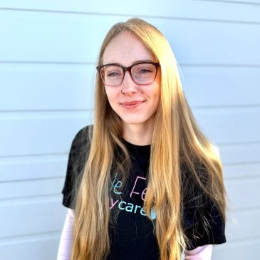 Smiling young woman with long blonde hair and glasses.