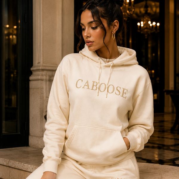 Woman in cream hoodie with CABOOSE text.