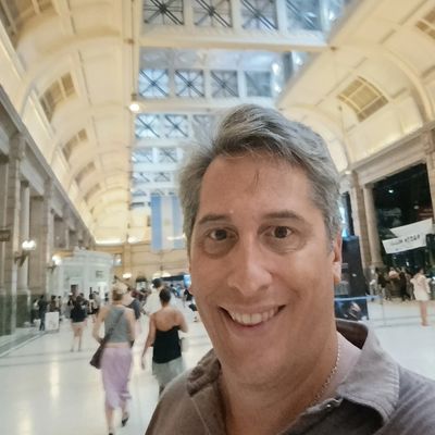Man smiling in a busy, spacious train station or terminal.