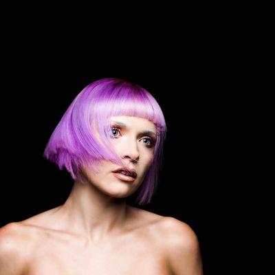 Model with pale skin and pink bob hair style with a blunt fringe looking to the right. 