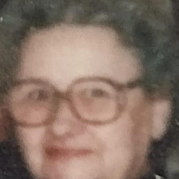 An elderly person with glasses and curly hair.