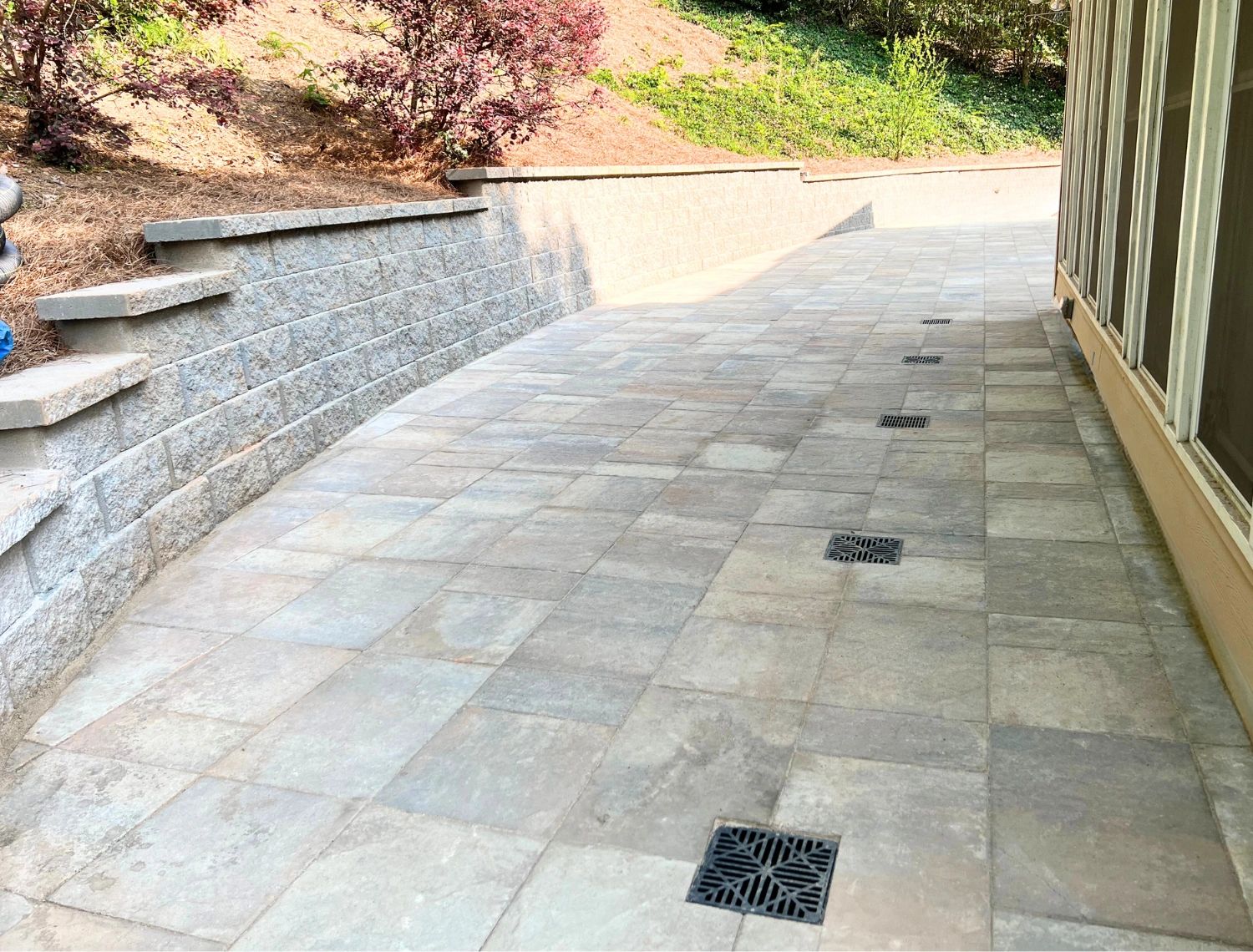 a backyard patio and retaining wall made from concrete paver blocks