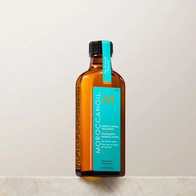 Bottle of Moroccanoil hair treatment on a marble surface.