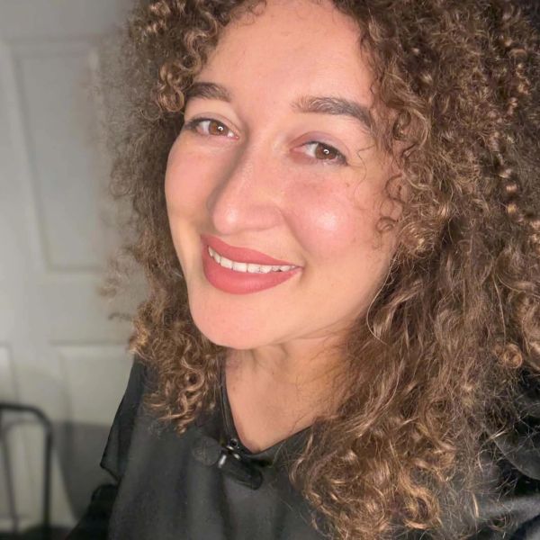 Smiling woman with curly hair and natural makeup.