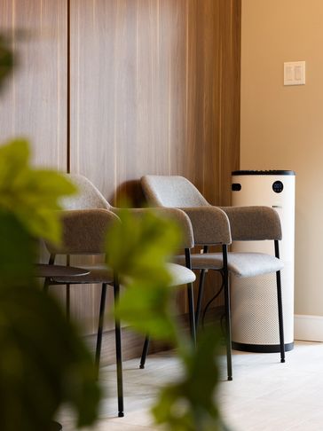Modern waiting area with two gray chairs and a white air purifier.