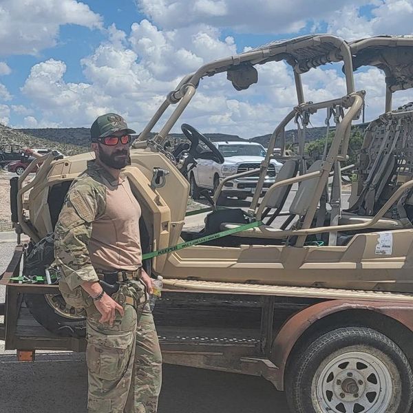 The owner of Haven Defense Group standing in camo next to a offroad vehicle that is on a trailer
