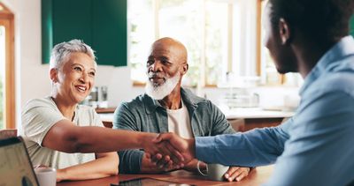 Couple shaking hands with a man in an office.