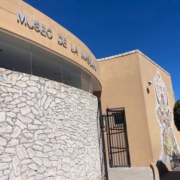Exterior view of Museo de la Máscara with stone and beige walls under a clear blue sky.