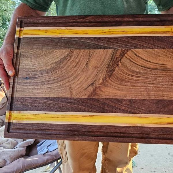 Handcrafted wooden cutting board with mixed wood tones and yellow accents.
