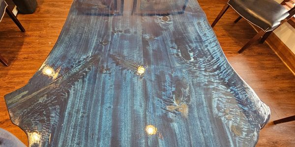Glossy blue wooden table with natural grain patterns in a room with chairs.