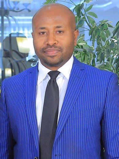 Man in a blue pinstripe suit with a black tie.