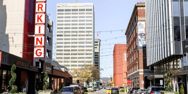 Urban street scene with parked cars and buildings under a clear sky.
