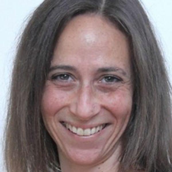 Smiling woman with long brown hair against a plain background.