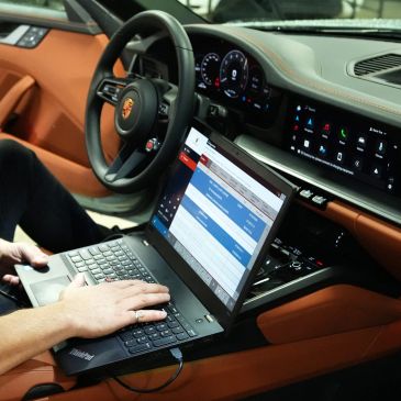 Person using a laptop inside a luxury car.