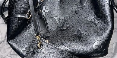 Black Louis Vuitton handbag and matching pouch with embossed monogram pattern.