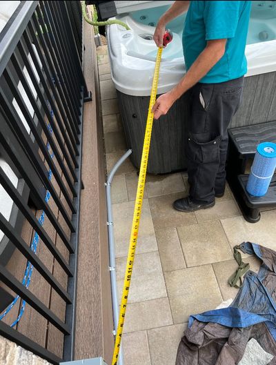 A technician measuring the distance between the disconnect and a hot tub / spa. 