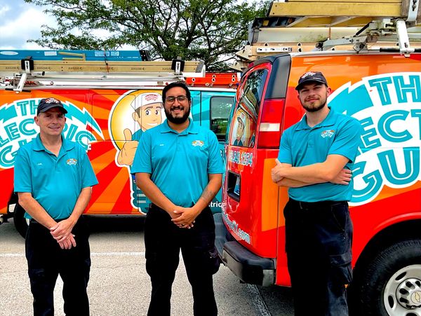 Carl, Ryan and Brandon standing in front of 2 Electric Guys vans. All are wearing uniforms and smili