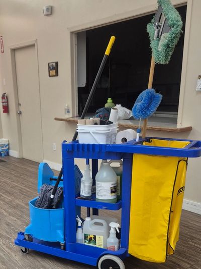 A janitorial cart with cleaning supplies and tools indoors.