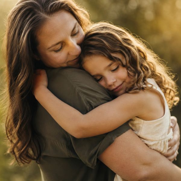Mother and daughter sharing a warm embrace outdoors.