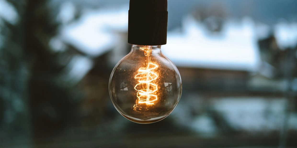 Glowing vintage light bulb with a coiled filament in focus.
