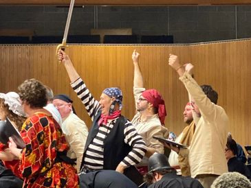 Actors performing a lively pirate-themed scene on stage.
