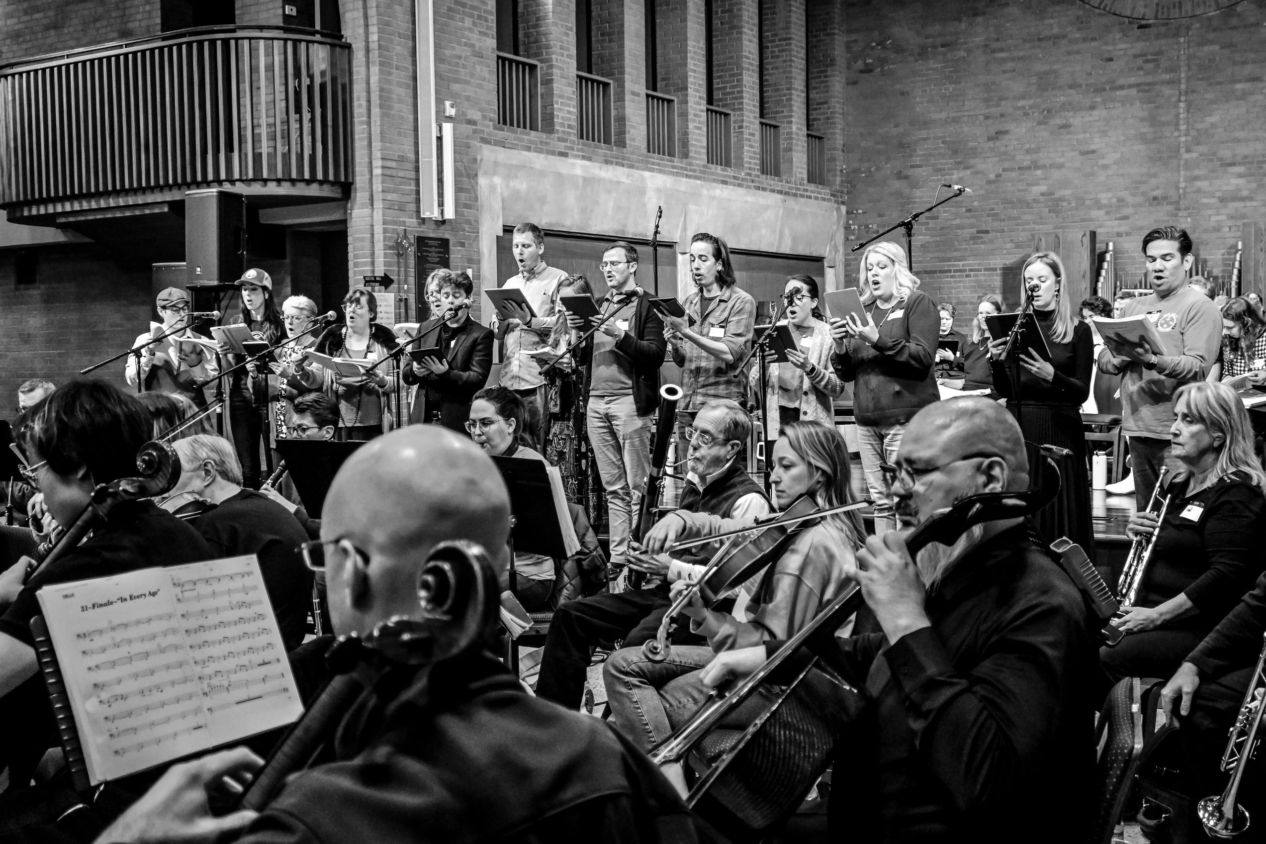 Choir and orchestra performing together in a large indoor venue.
