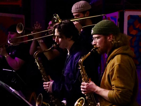 Musicians playing saxophones and trombones in a band.