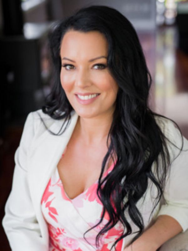 Smiling woman with long black hair wearing a white blazer.