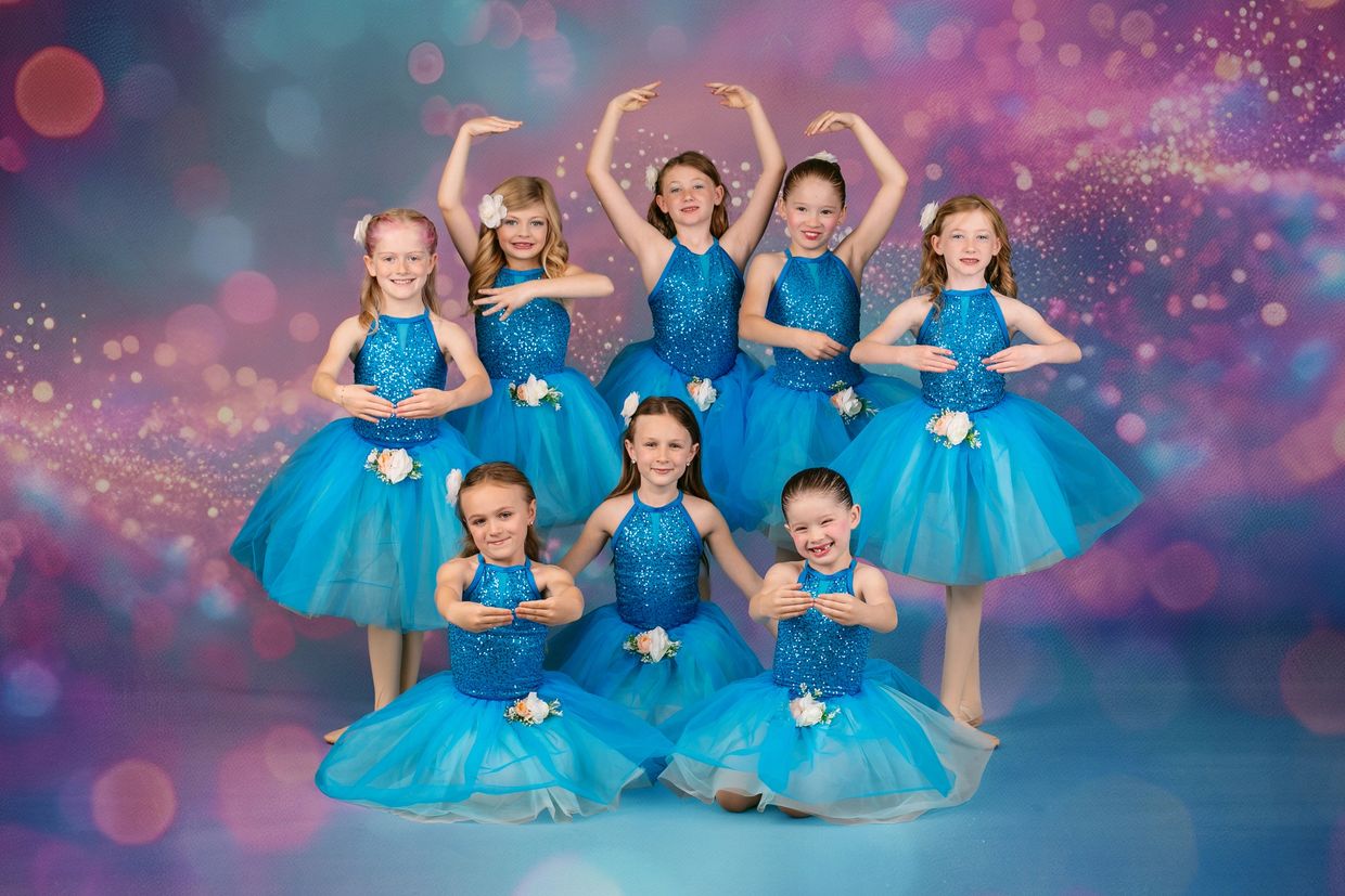 Young ballerinas in blue sequined tutus pose gracefully together.