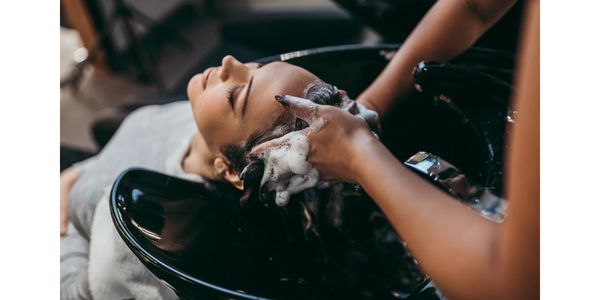 A woman enjoying a shampoo at a salon.