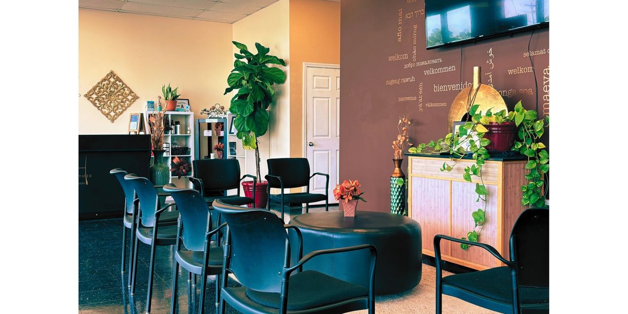 Cozy waiting area with black chairs, plants, and warm decor.