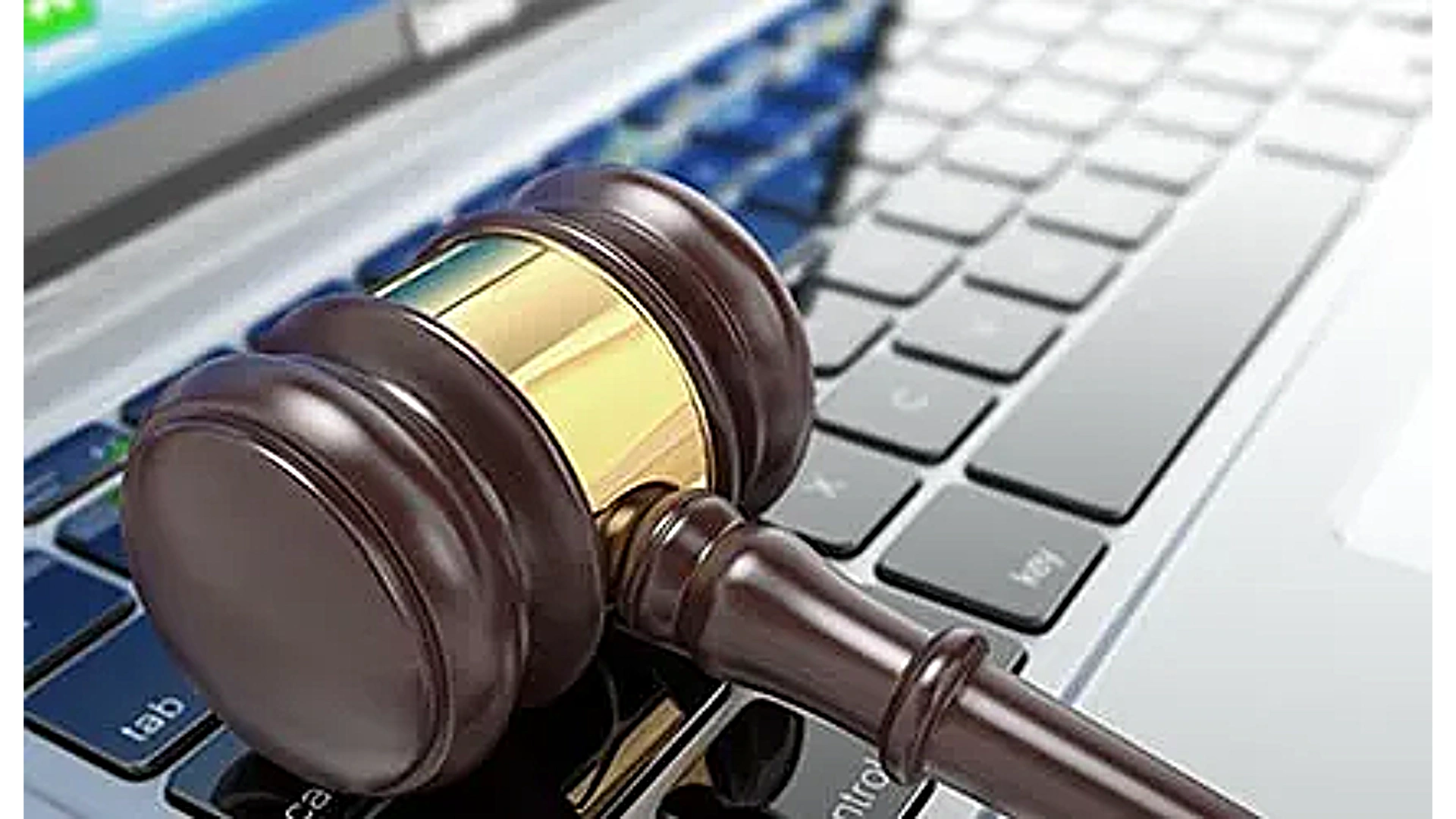 A wooden judge's gavel resting on a laptop keyboard.