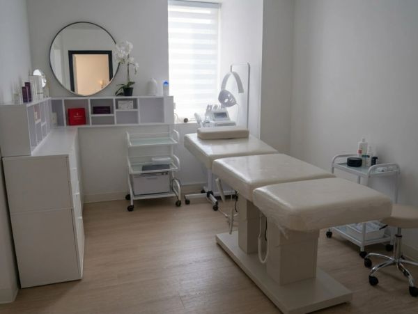 Minimalist medical treatment room with white decor and treatment beds.