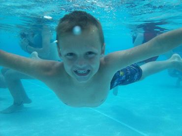 Child in a clean pool swimming under water