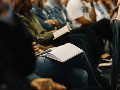 People sitting and taking notes during a meeting or lecture.