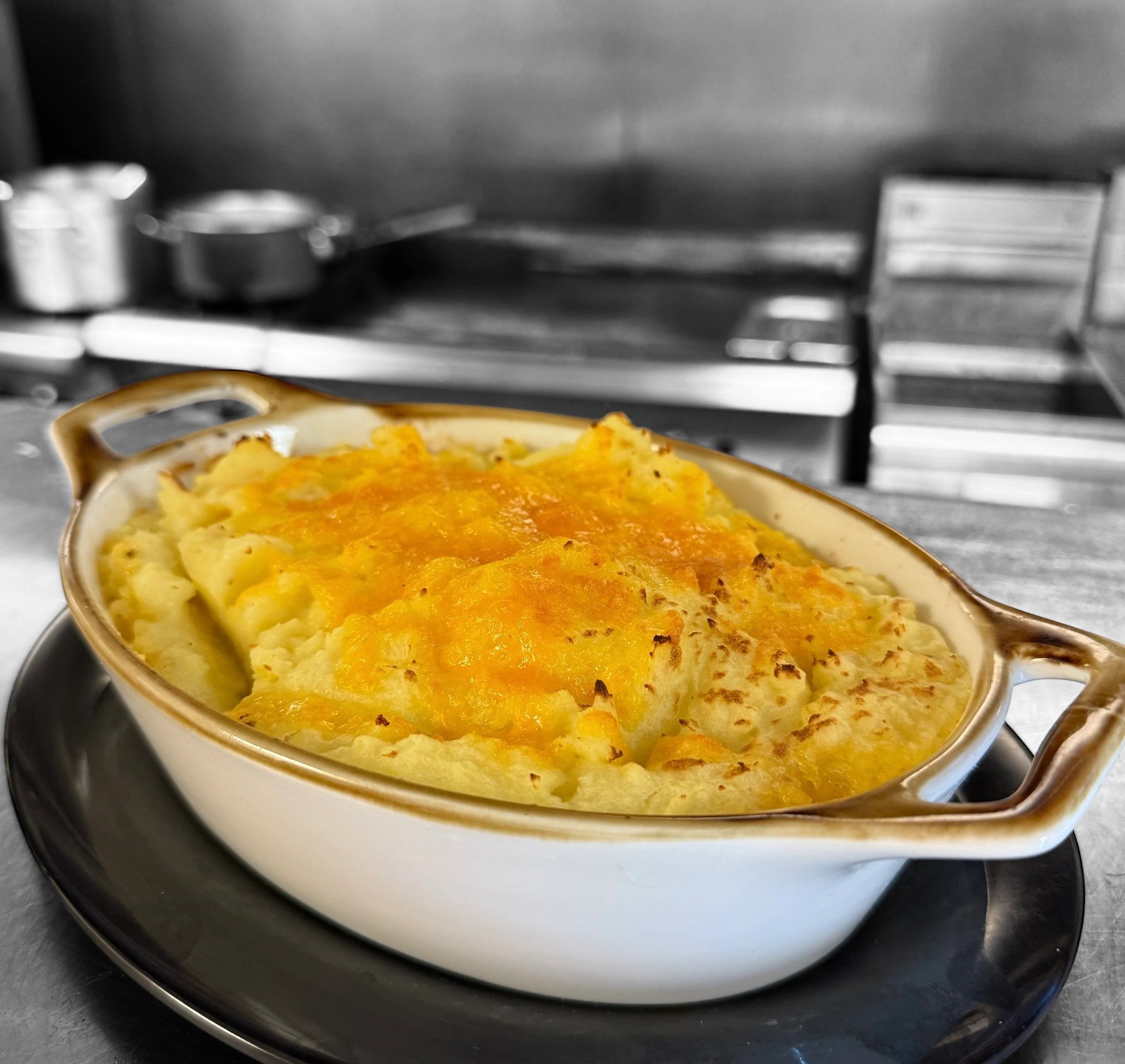 Baked cheesy mashed potatoes in a white casserole dish.