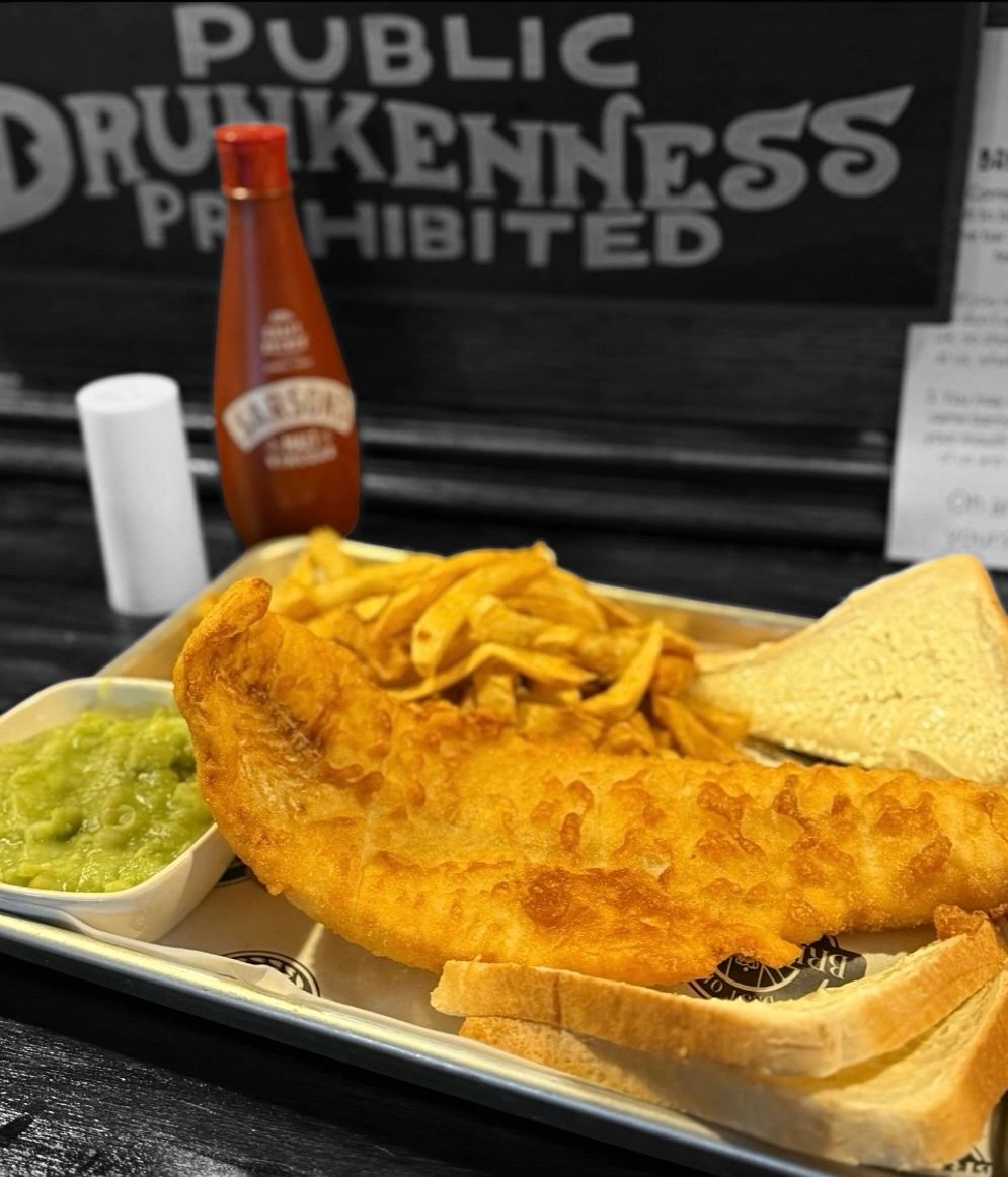Fish and chips with toast and mushy peas on a tray.
