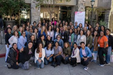 Large group of diverse women posing outdoors together.