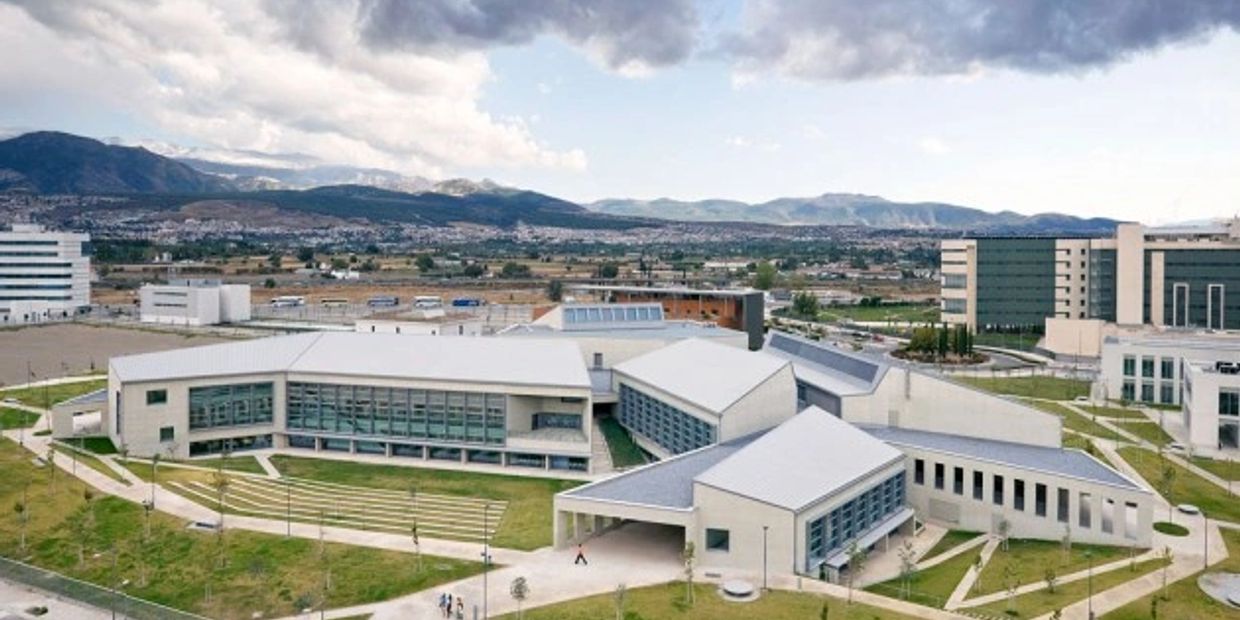 Modern university campus with multiple buildings and mountain backdrop.