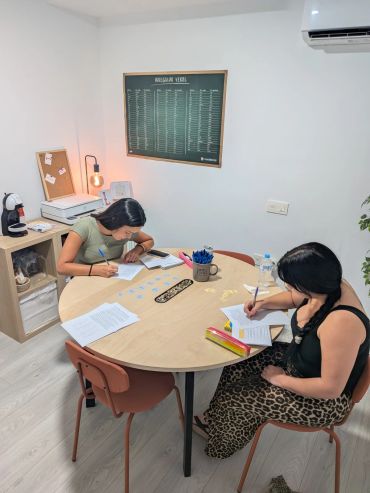 Dos mujeres estudiando juntas en una mesa redonda.