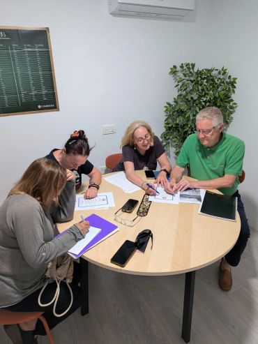 Cuatro personas concentradas trabajando en una mesa redonda.