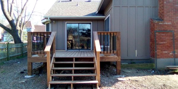 New wooden deck with stairs attached to a house's back entrance.