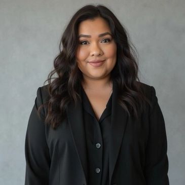 Confident woman with wavy hair in a black blazer smiles warmly.