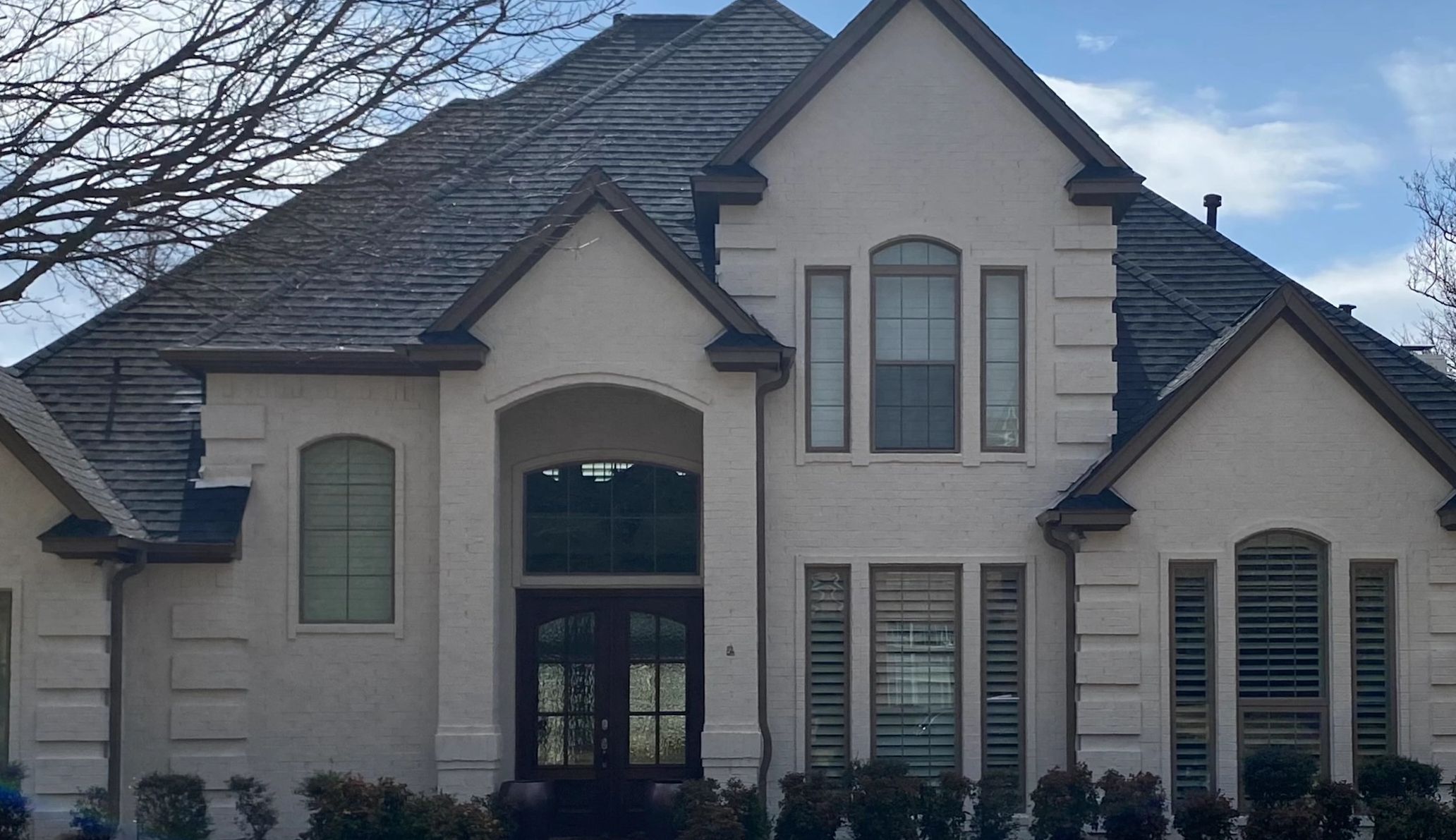 A large house with a dark roof and cream-colored walls.