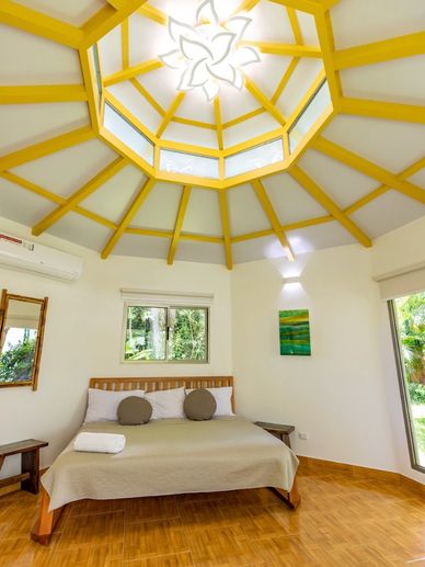 Bright bedroom with a unique yellow-beamed ceiling and a large bed.